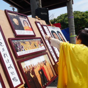 在八里放生法會現場，向當地的遊客講述「南無第三世多杰羌佛返老回春照」，及「因海公聖尊圓寂後以肉身大神變」所創下的佛史新聖蹟