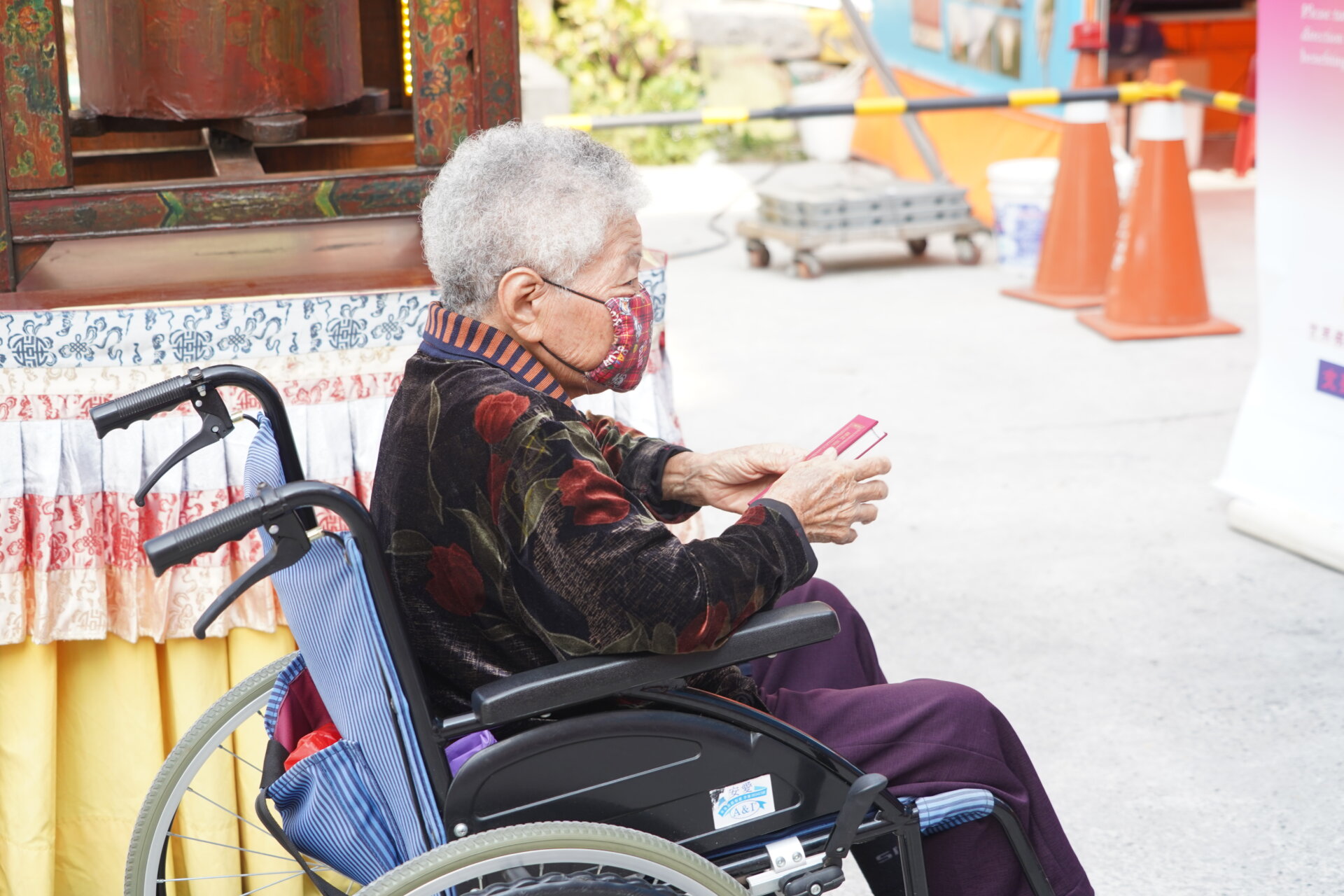 行動佛殿111站嘉義市地藏庵旁，年老的信眾坐著輪椅恭敬誦經