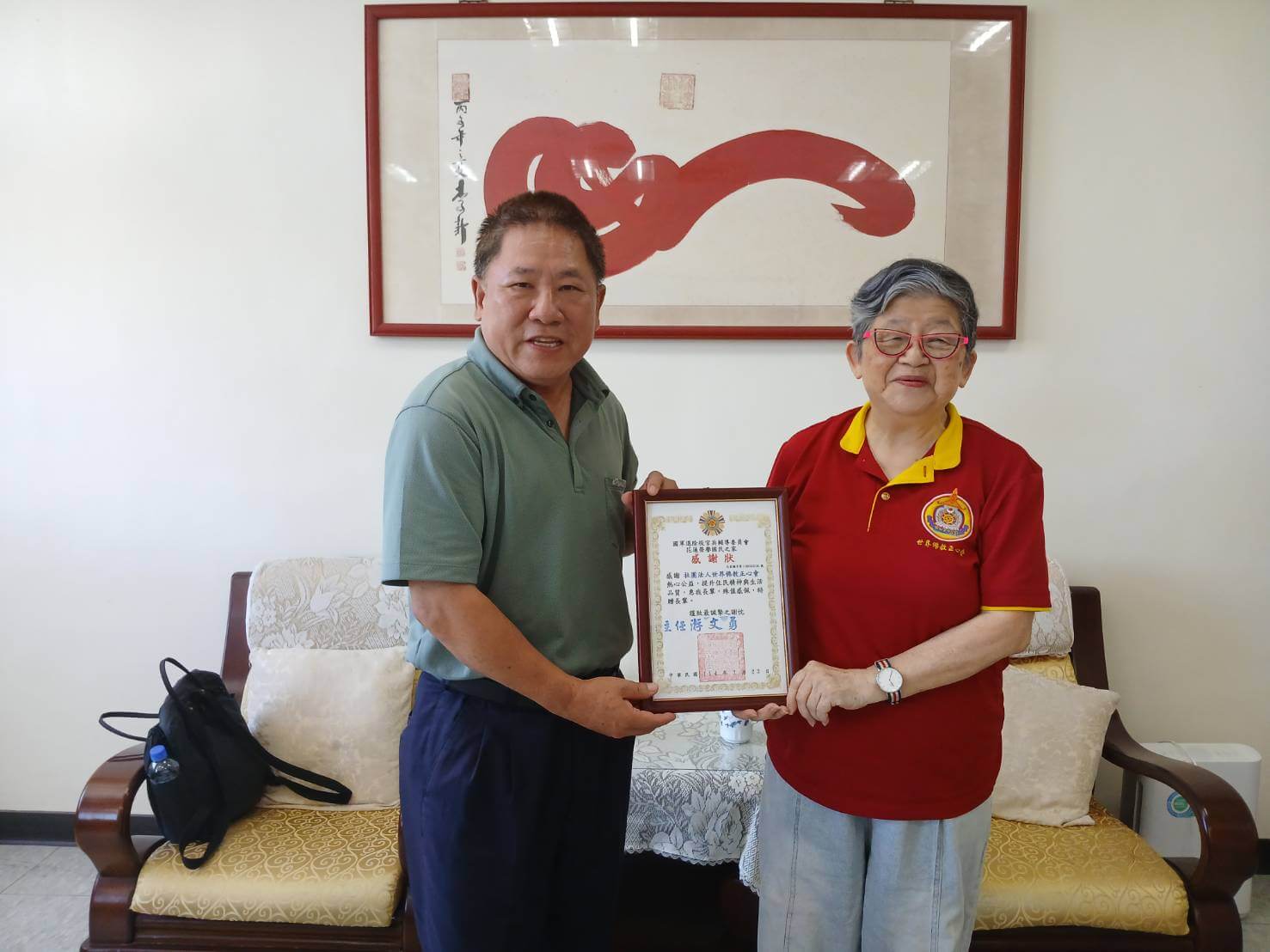 世界佛教正心會至花蓮榮服處公益關懷，本會陳和慧執行長(右)捐贈加菜金，榮家家主任游文勇(左)特別回贈感謝狀