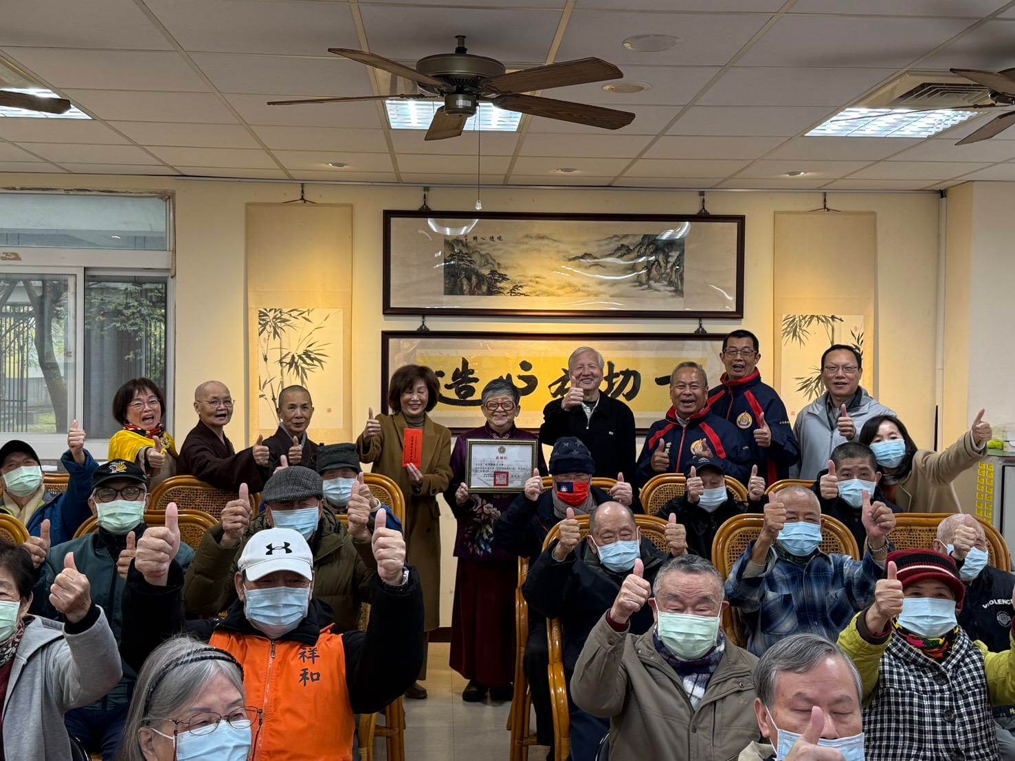 世界佛教正心會致贈板橋榮家榮民伯伯加菜金,該會執行長陳和慧與榮家家主任陳桂美及現場榮民伯伯合影